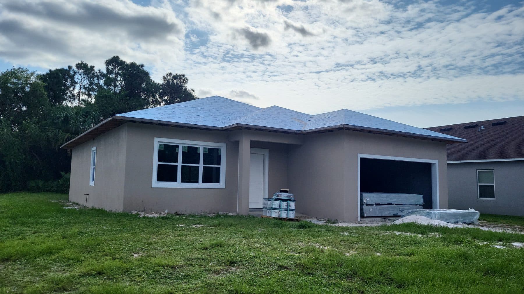 Residential home exterior with completed stucco, installed windows, and roof underlayment